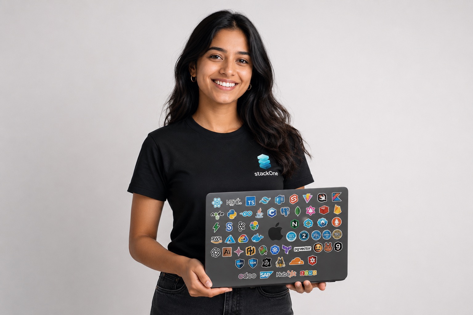 An intern holding a laptop covered in stickers for every technology in the StackOne stack